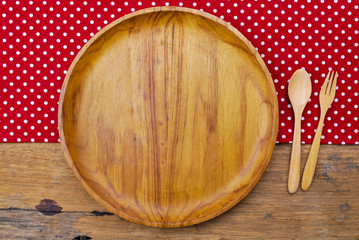 Wooden plate, tablecloth, spoon, fork on old table background