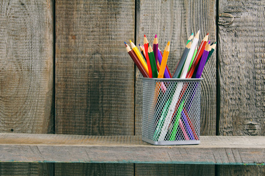Pencils on a wooden shelf.