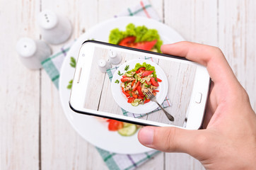 Hands taking photo vegetable salad with smartphone