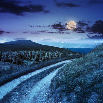 road on a hillside near mountain peak at night