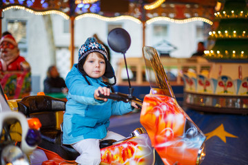 Fototapeta na wymiar Adorable little child on a carousel at Christmas funfair or mark