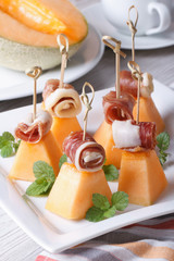 Italian appetizer: melon with ham on skewers vertical