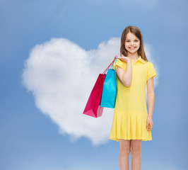 smiling little girl in dress with shopping bags