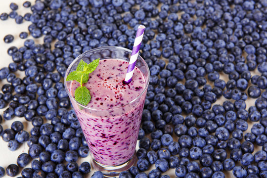 Blueberry smoothie in a glass jar with a straw and sprig of mint