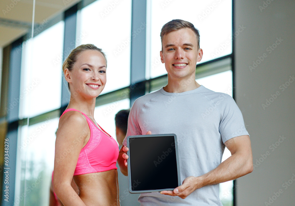 Sticker smiling young woman with personal trainer in gym