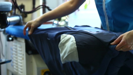 View of laundry worker ironing jacket