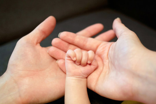 Hands of father, mother and newborn baby.