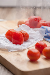 Red small tomatoes on wood board.