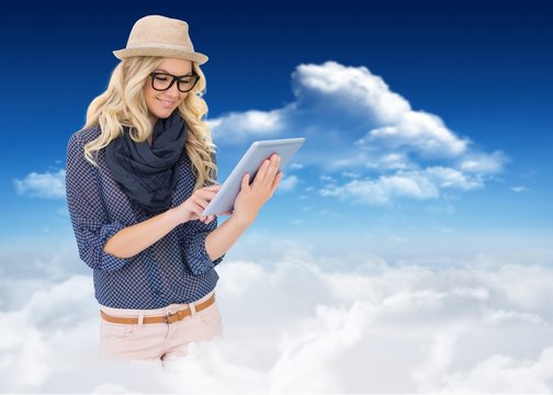 Composite image of smiling trendy blonde using tablet computer