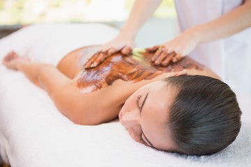 Attractive woman receiving chocolate back mask at spa center