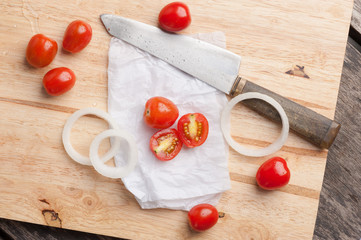 Red small tomatoes on wood board.