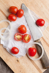 Red small tomatoes on wood board.