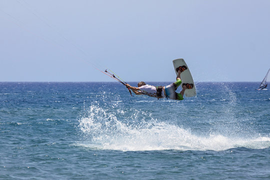 a boy engaged in an acrobatic leap to kitesurf