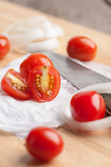 Red small tomatoes on wood board.