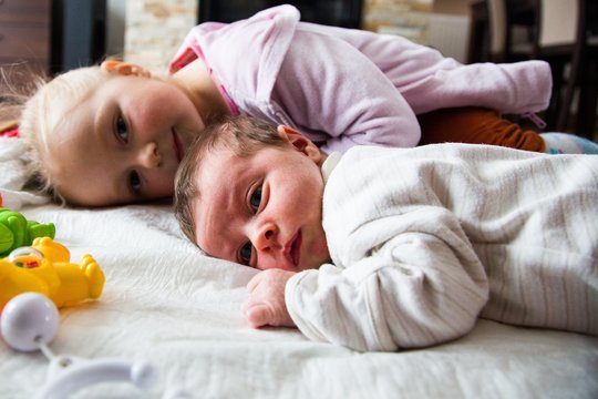 Happy infant girl with newborn sister