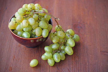 Fresh white grapes in ceramic plate on the wooden table