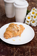 coffee, croissant and a bouquet of daisies