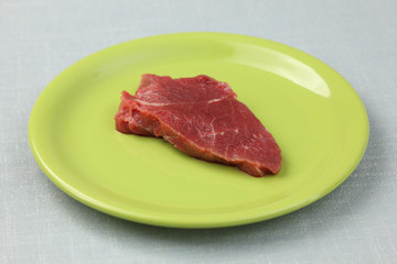 Raw fillet beef steak on a green plate