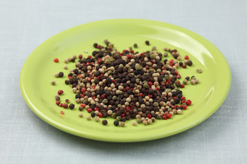 Mixed peppercorns on a green plate