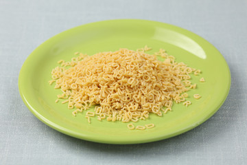 Raw alphabet soup pasta on a green plate