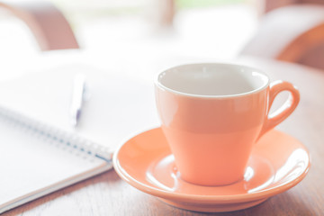 Orange coffee cup with pen and notebook