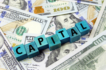 word capital on wooden cubes on american dollars background