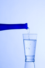 Wasserglas mit blauer Flasche