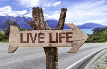 Live Life wooden sign with a street background