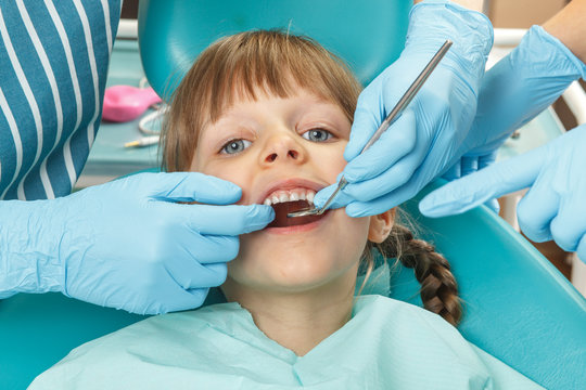 Close-up of little girl having her teeth checked by dentist