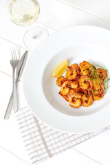 Shrimp dish on a white plate and a glass of white wine