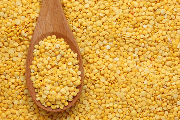 Yellow lentils in a wooden spoon