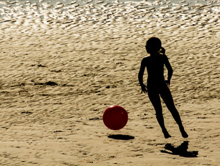 Niña jugando con balón en la playa