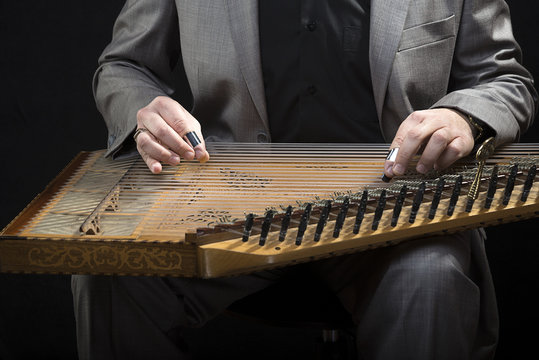 Classic musician playing kanun over black background