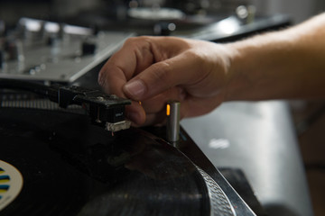 Closeup portrait of dj hands on equipment deck and mixer with vi