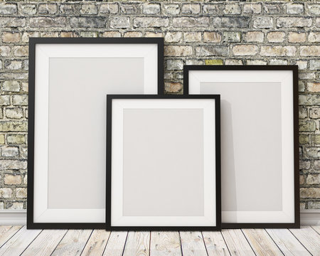 three blank black picture frames on the old brick wall