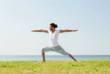 smiling man making yoga exercises outdoors