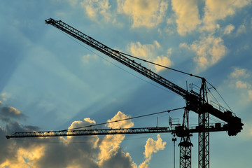 Construction cranes against of the sun