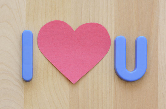 Close up of I love U in plastic toy letters and pink flat heart