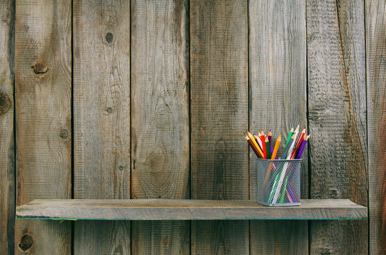 Pencils on a wooden shelf.