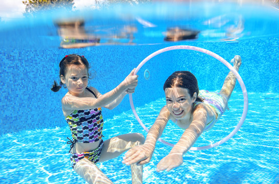 Happy active kids swim in pool and play underwater