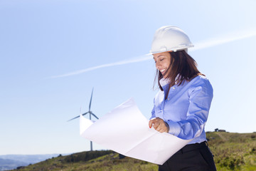 Female engineer holding a blueprints at wind farm