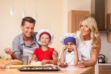Young parents cooking together with children.