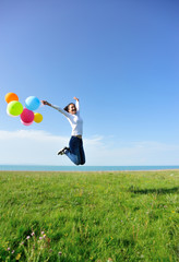 young asian woman on green grassland with colored balloons 