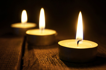 Burning candles. On wooden background.