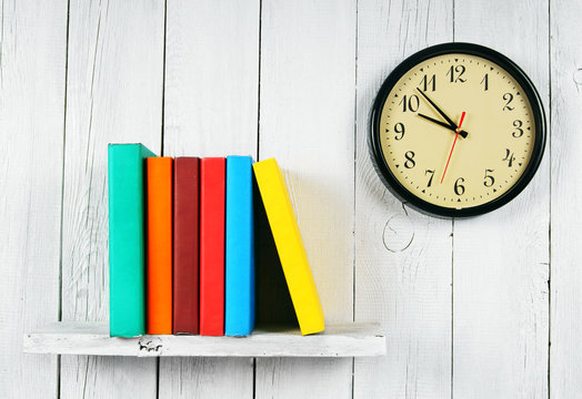 Watches and books on a wooden shelf.