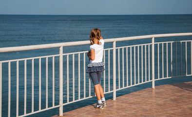 Girl walking along  waterfront and looking at the sea