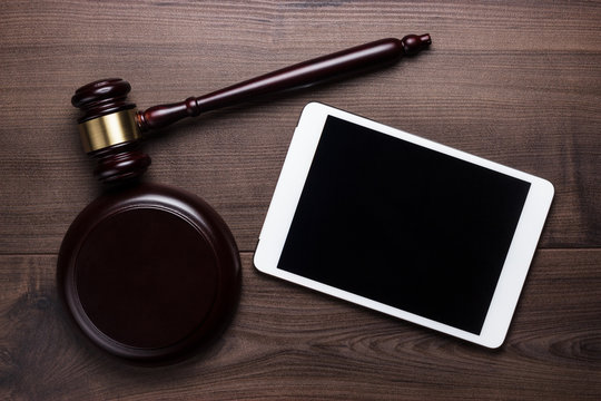 judge gavel and tablet computer on brown wooden backgroundjudge