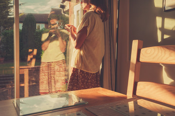 Young woman standing by french doors at sunset