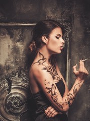 Smoking tattooed beautiful woman  in old spooky interior
