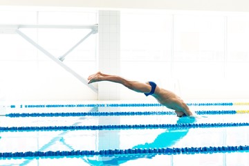Young swimmer jumping from starting block 